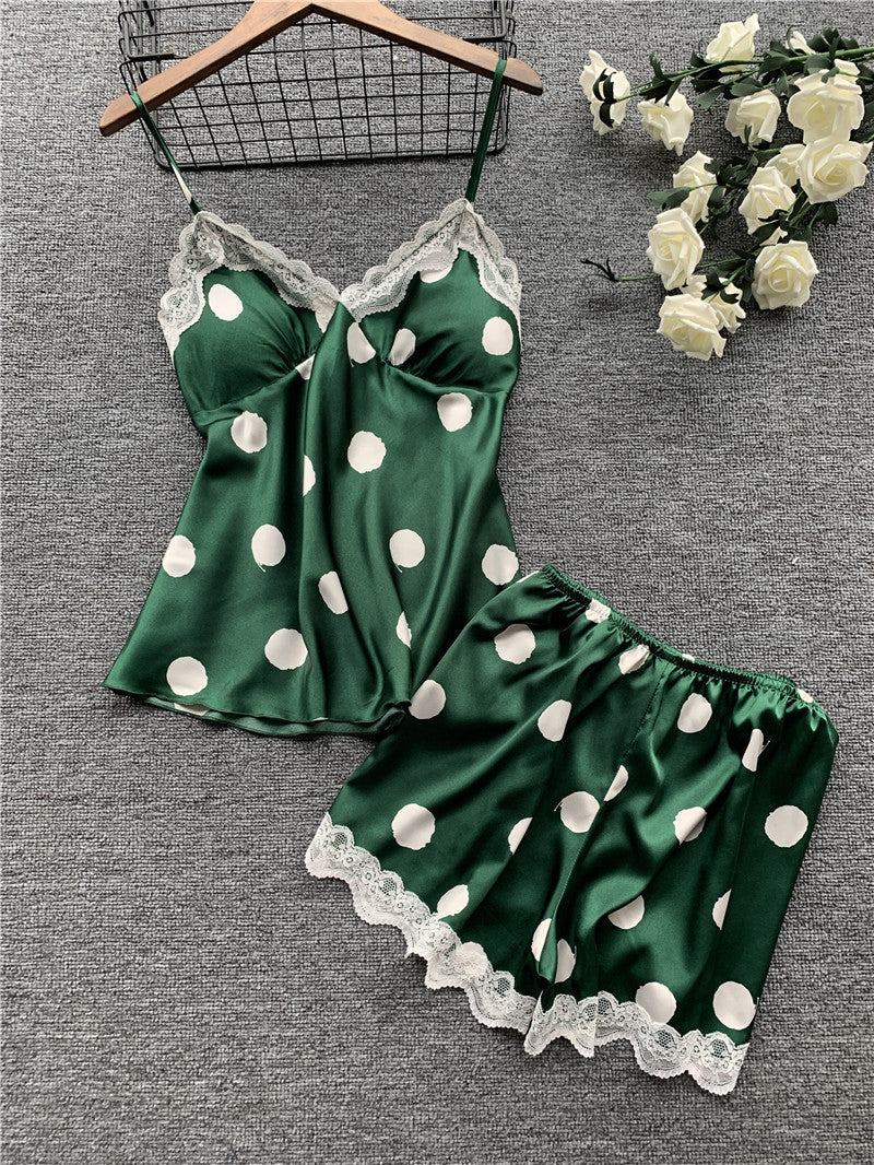 Green polka dot pajama set with lace trim on a gray surface with flowers.