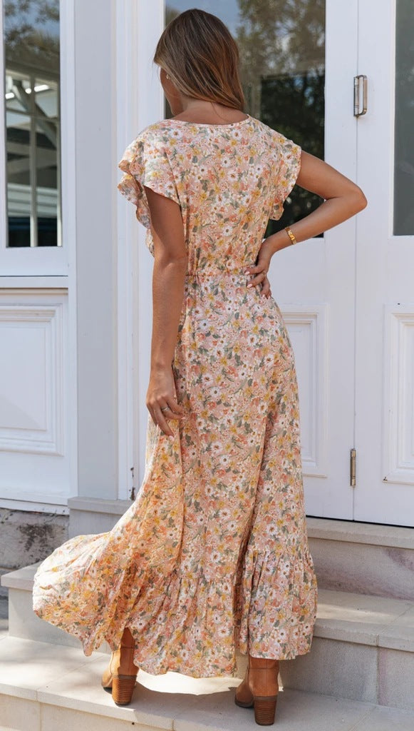 Woman in a floral dress standing on steps outside a white building.