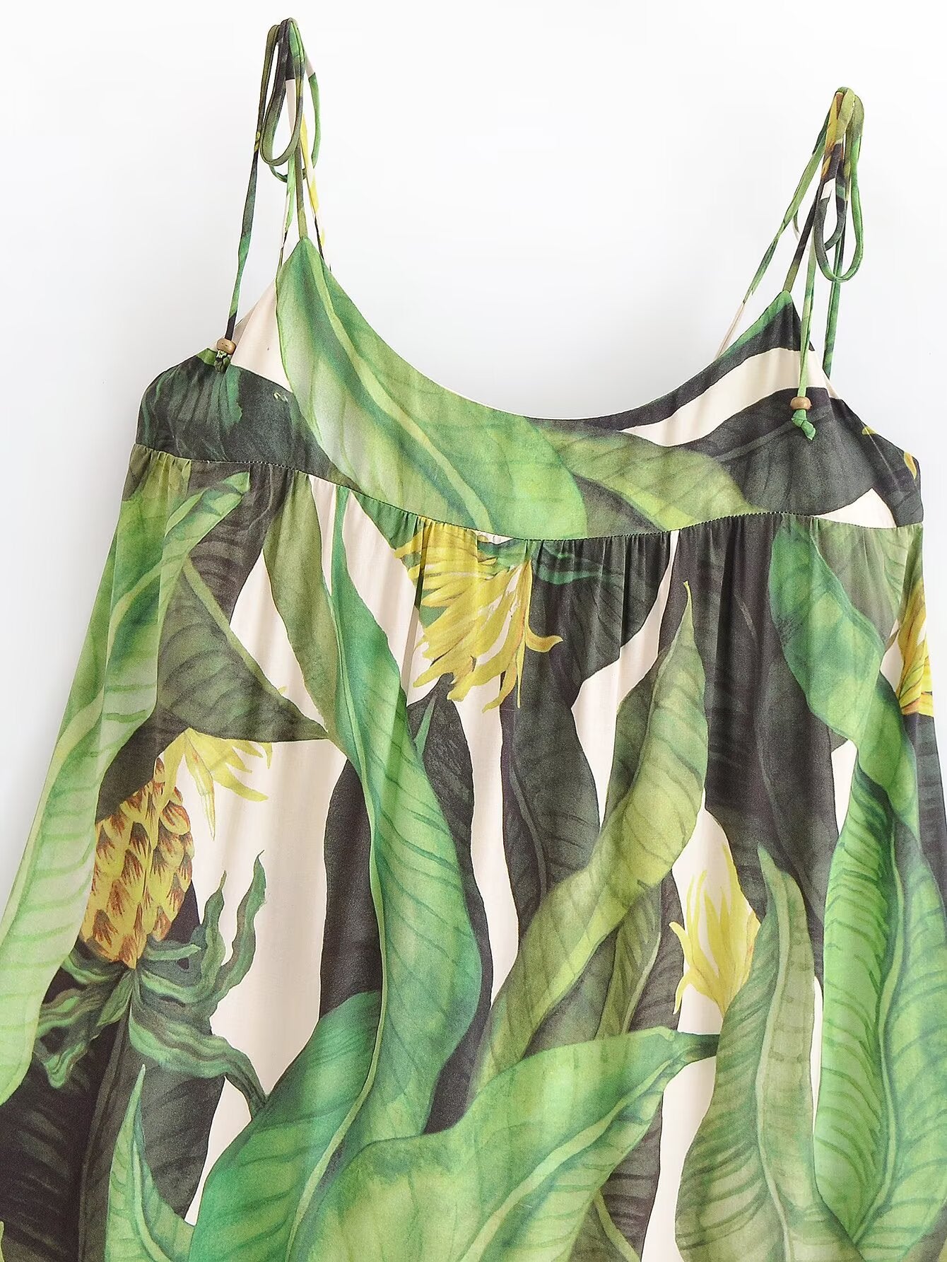 Tropical leaf patterned dress hanging against a white background