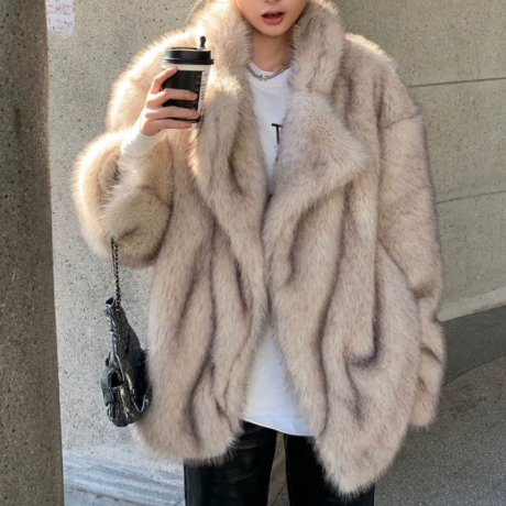 Person wearing a fur coat holding a coffee cup against a neutral background
