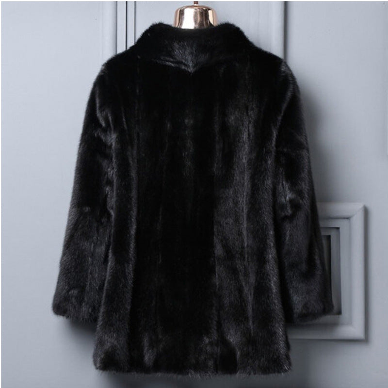 Black fur coat on a mannequin against a light gray wall.