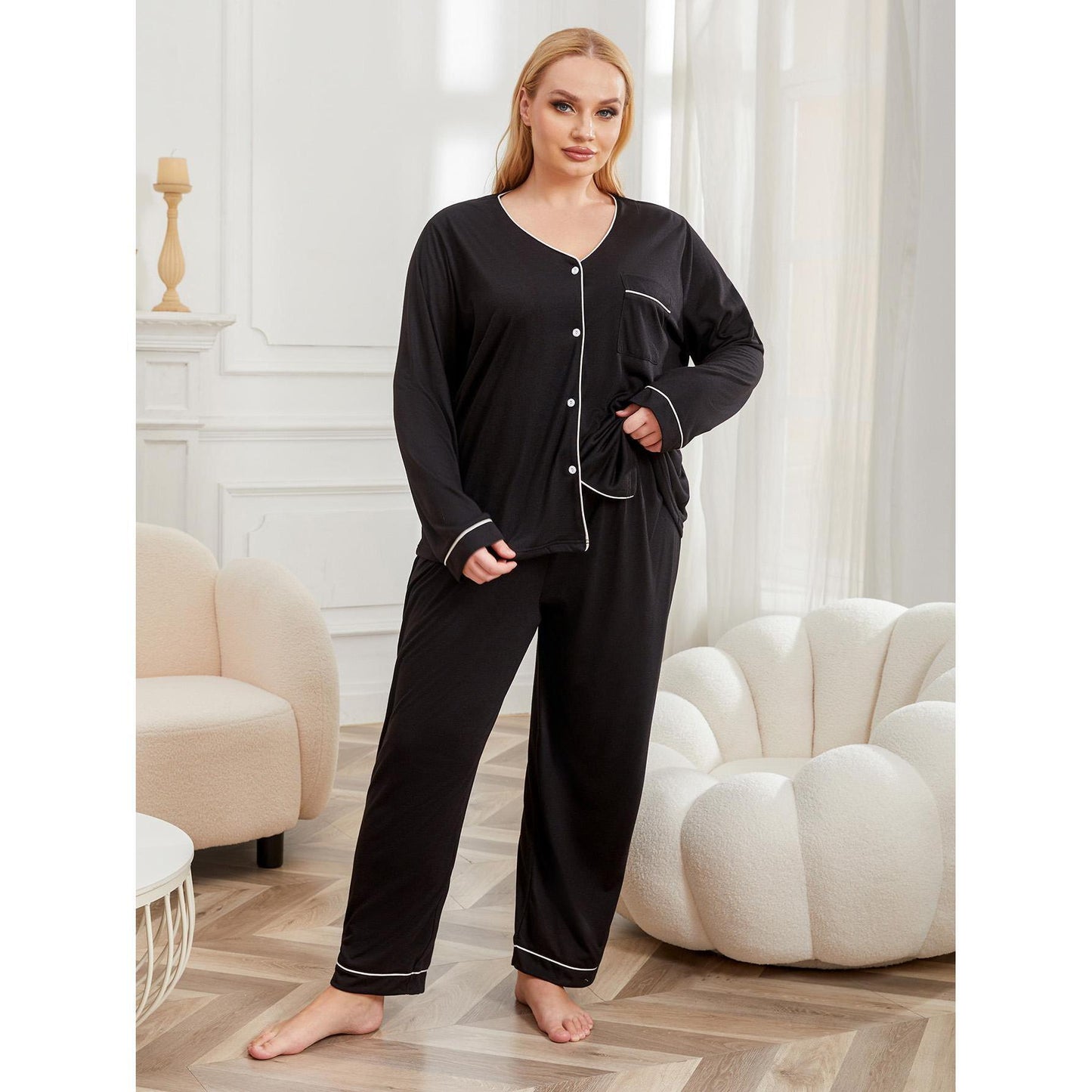 Woman wearing a black pajama set in a stylish room with white walls and furniture.