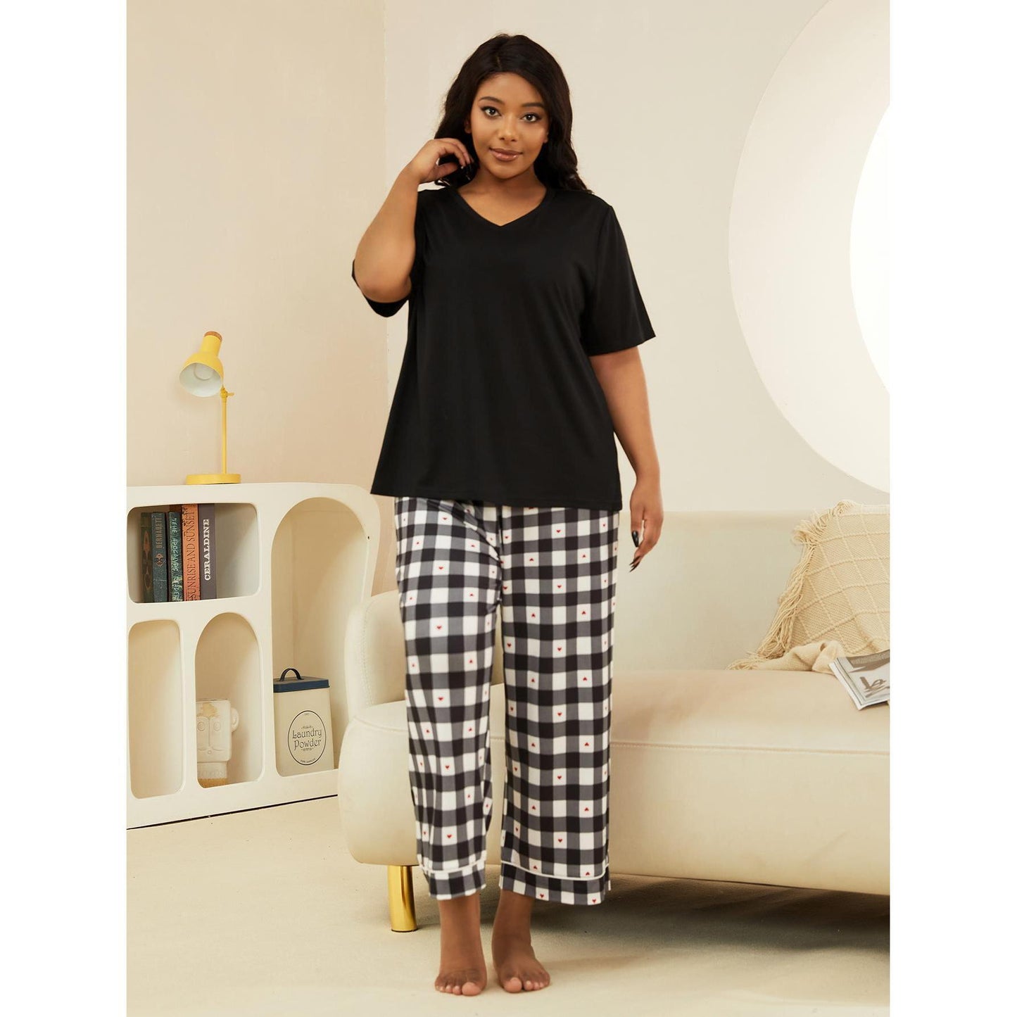 Woman wearing a black top and checkered pants in a living room setting.