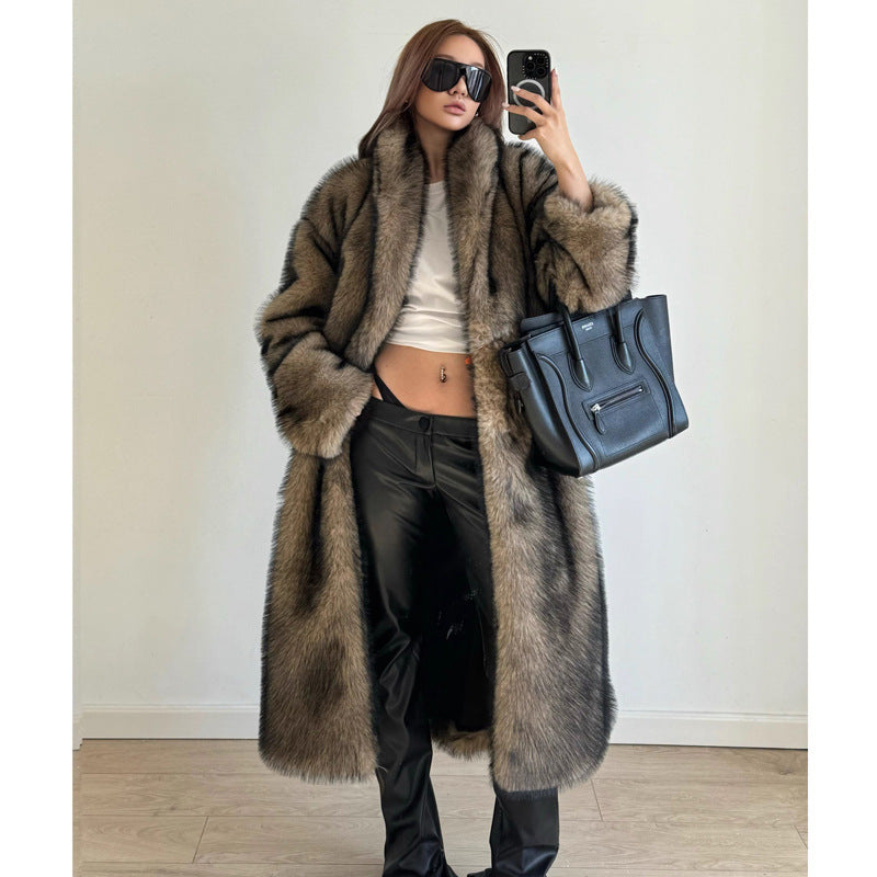 Person wearing a long fur coat and holding a black handbag indoors.