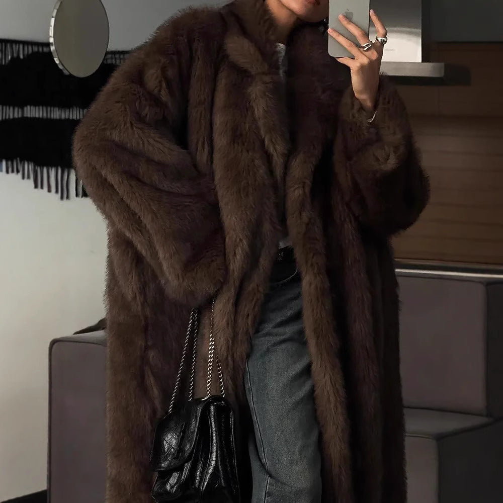 Person wearing a brown fur coat taking a selfie indoors.
