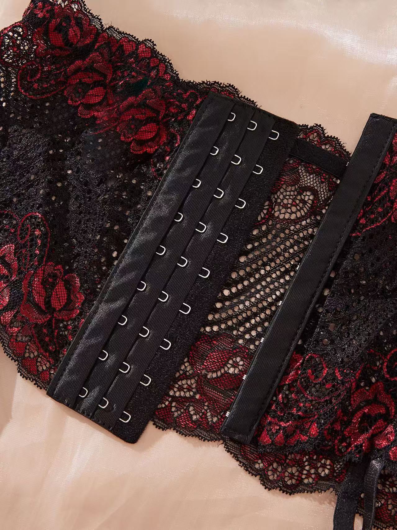 Black lace corset with red floral patterns on a beige background