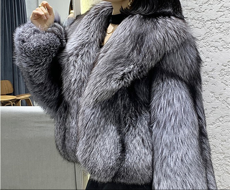 Person wearing a gray fur coat against a neutral background