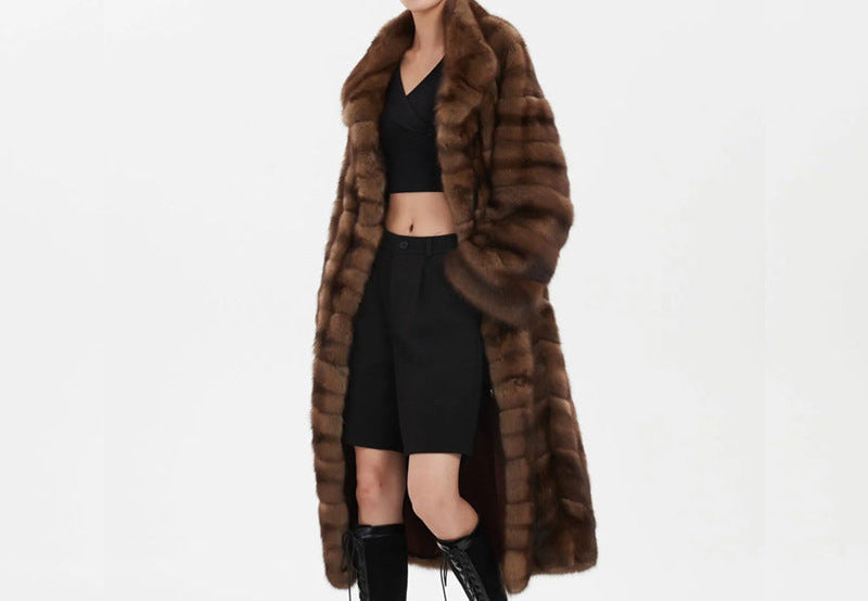 Woman wearing a long brown fur coat on a white background