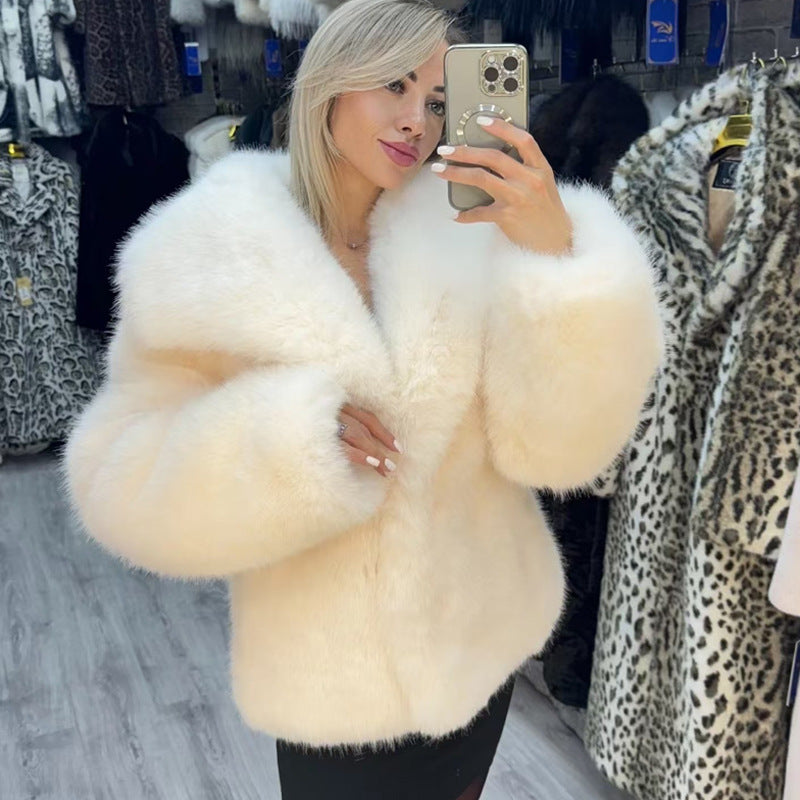 Woman wearing a fluffy white coat taking a mirror selfie in a clothing store.
