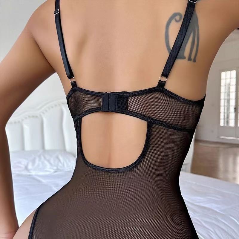 Person wearing a black mesh lingerie set in a bedroom setting