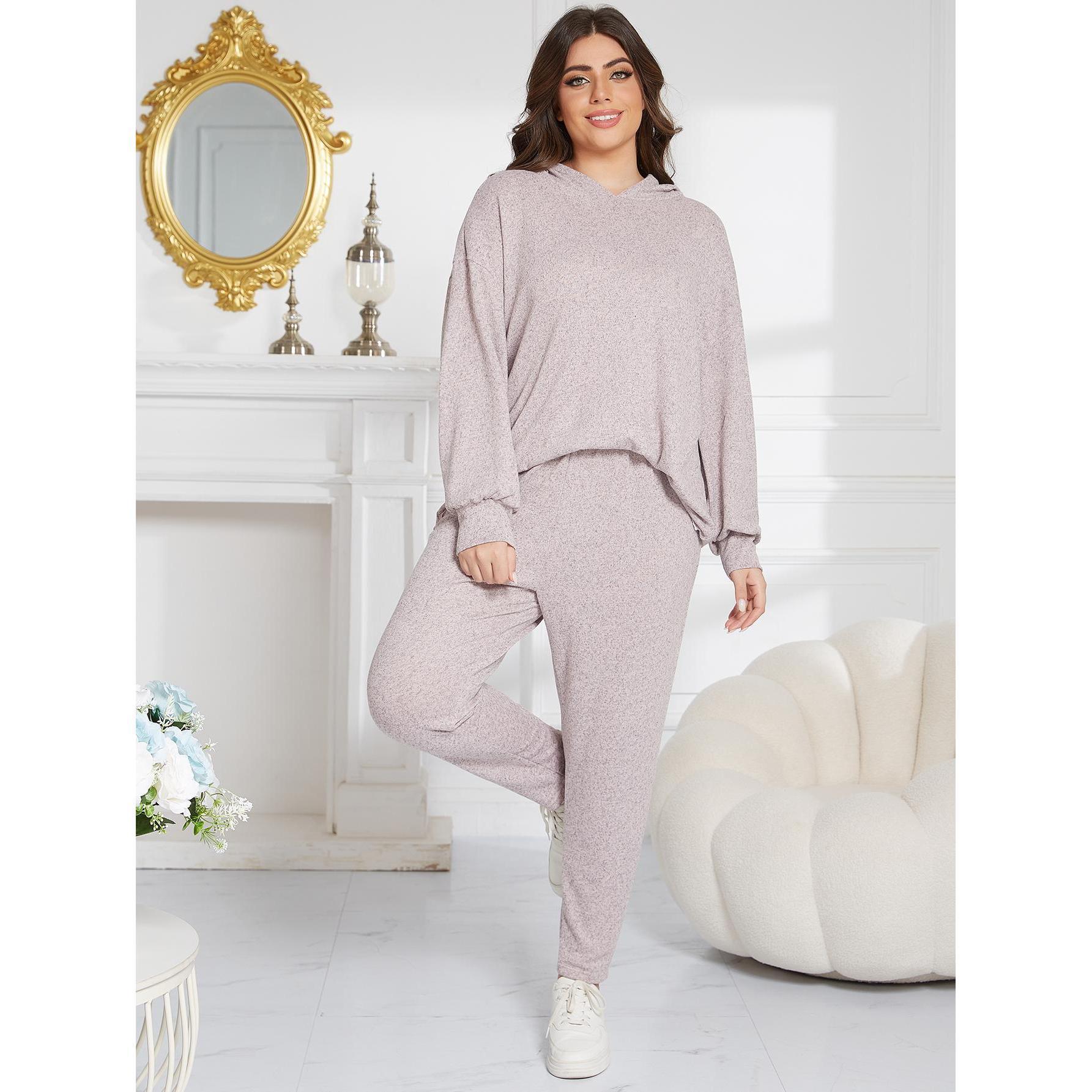 Woman wearing a light pink loungewear set in a bright room with decorative elements.