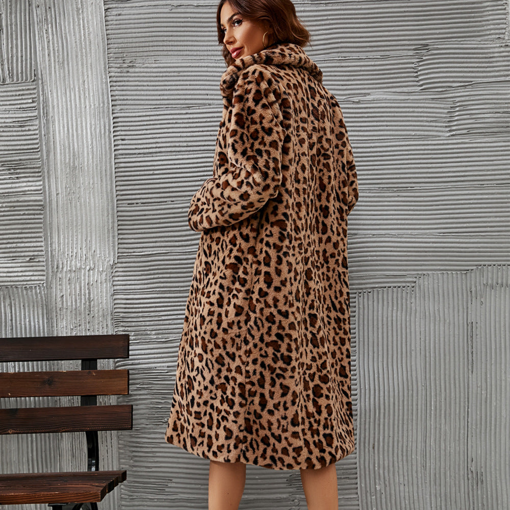 Woman wearing a leopard print coat standing against a textured wall.