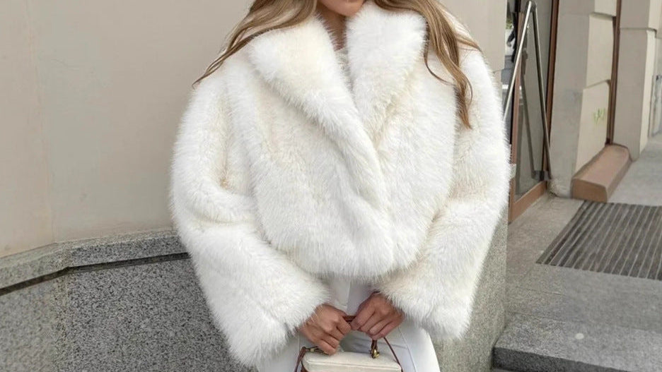Woman wearing a white fur coat and sunglasses, standing outdoors.