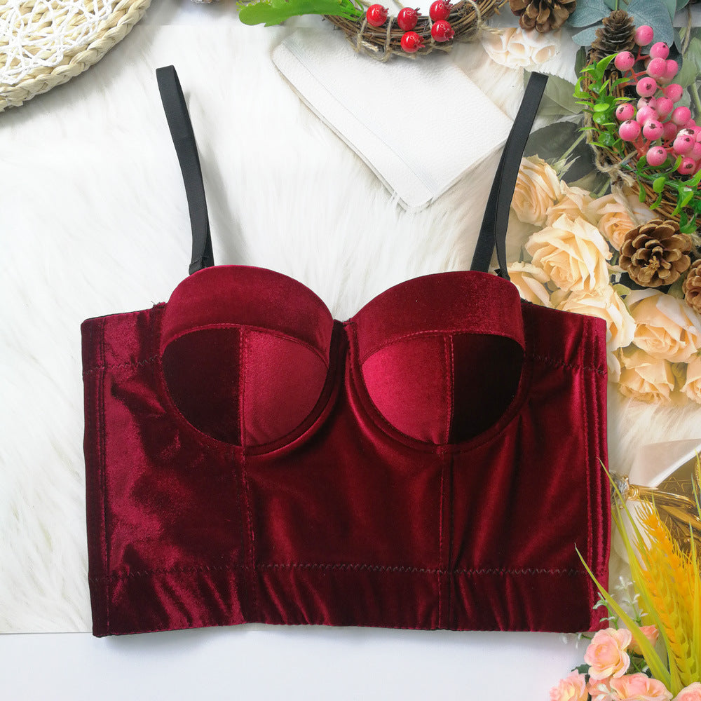 Red velvet bralette on a white surface with decorative elements.