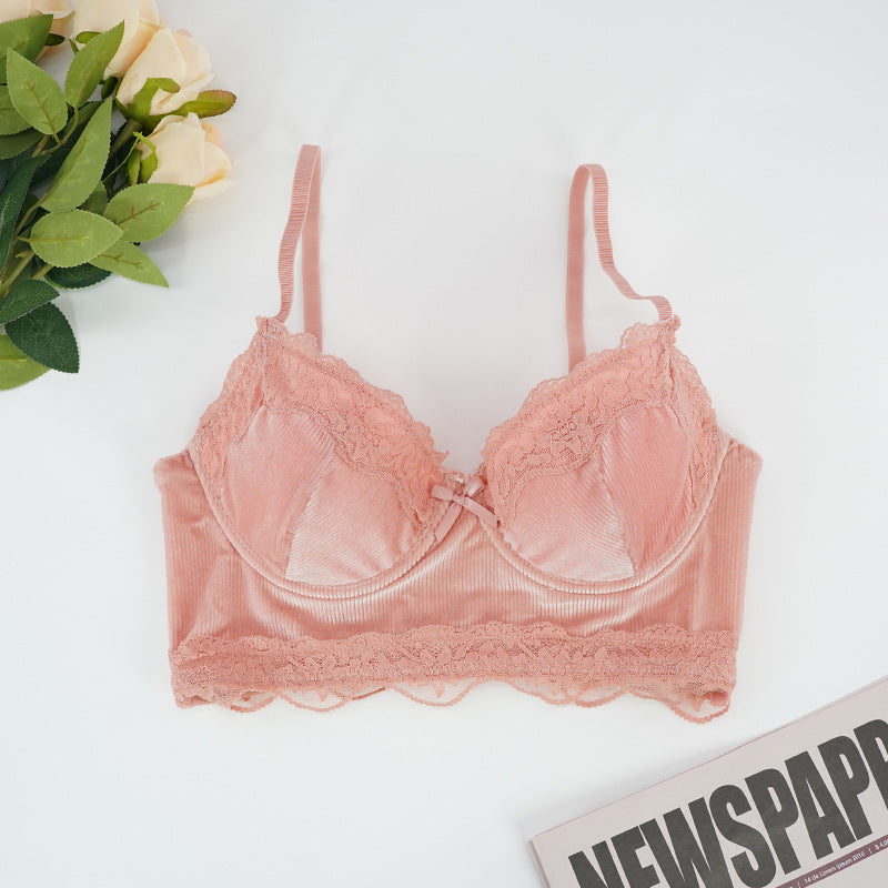 Pink lace bra on a white surface with flowers and newspaper in the background