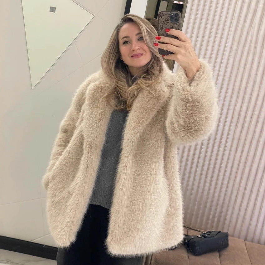 Woman wearing a beige fluffy coat taking a mirror selfie.