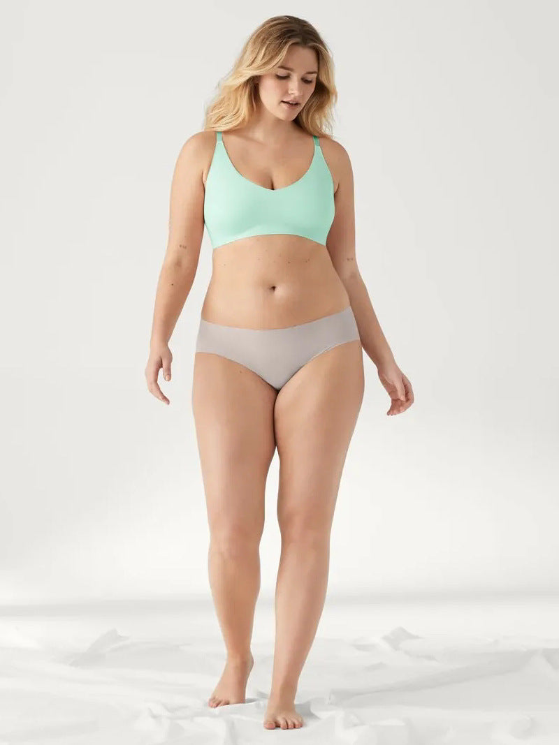 Woman wearing a mint green bra and gray underwear on a white background