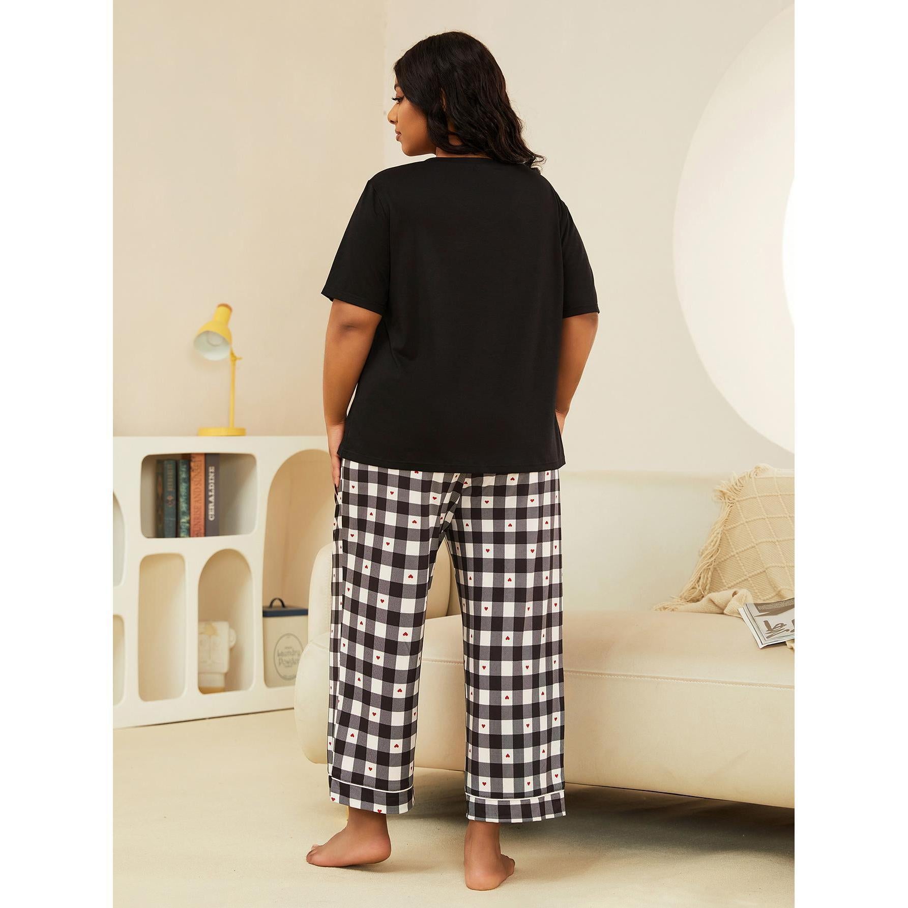 Person wearing a black t-shirt and checkered pants in a living room setting.