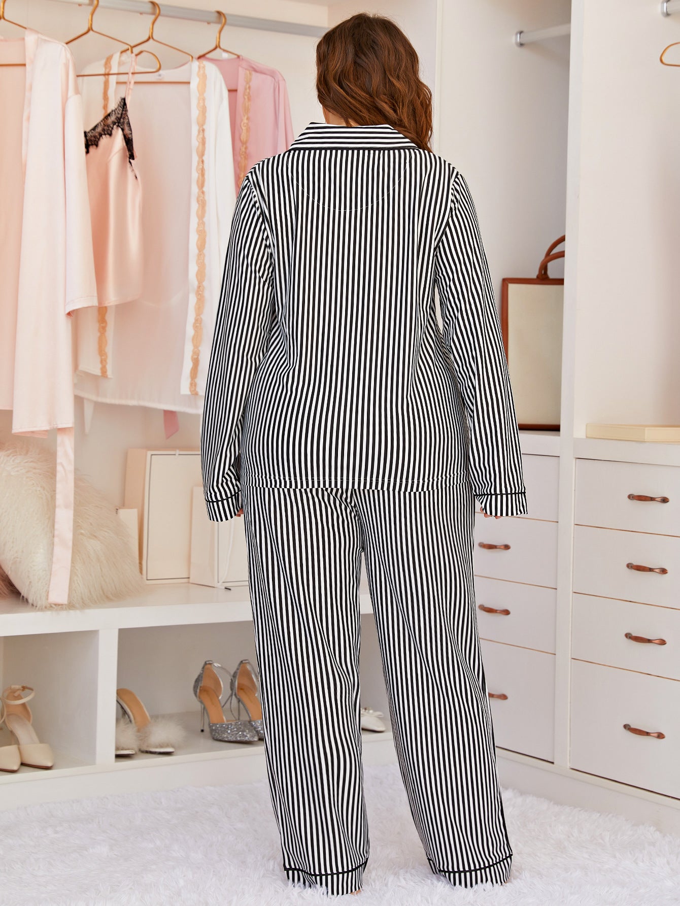 Person wearing a black and white striped pajama set in a bedroom.