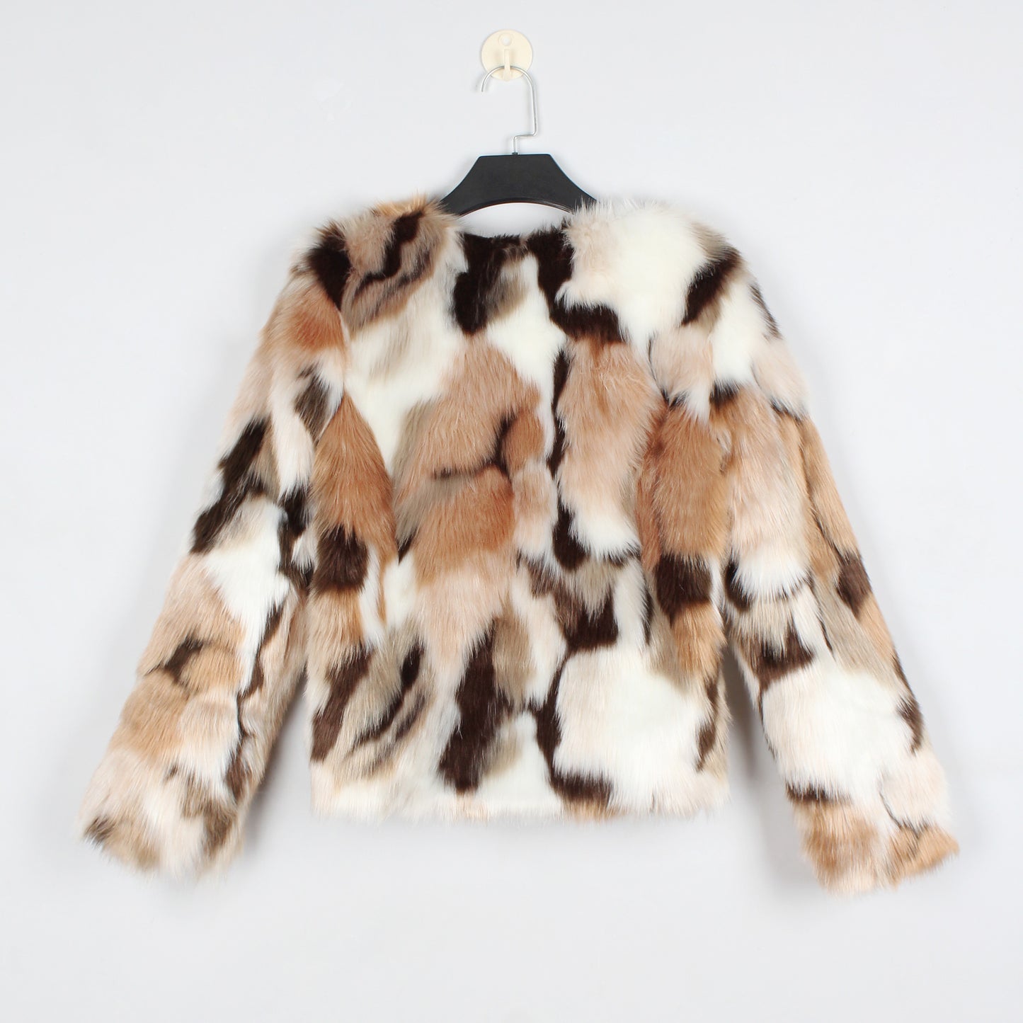Multicolored fur coat on a hanger against a light gray background