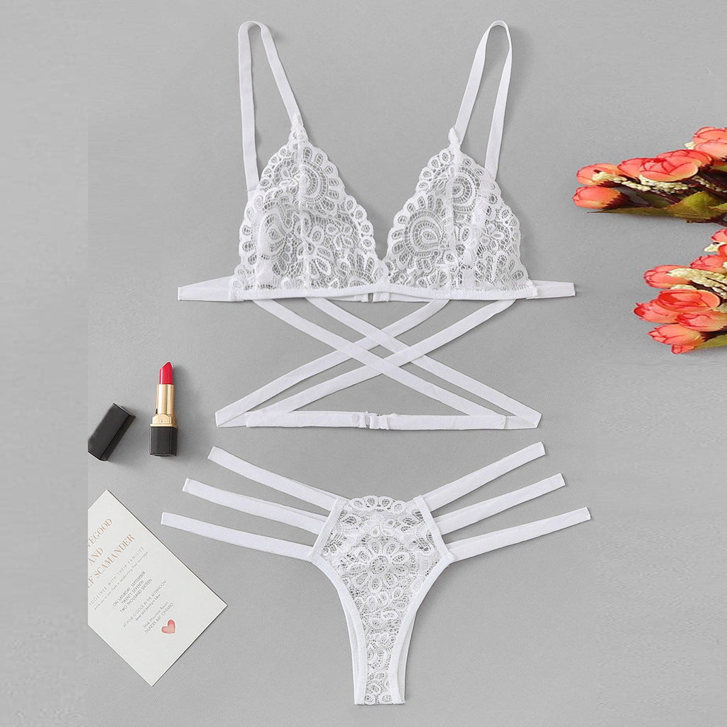 White lace lingerie set on a gray background with lipstick and flowers.
