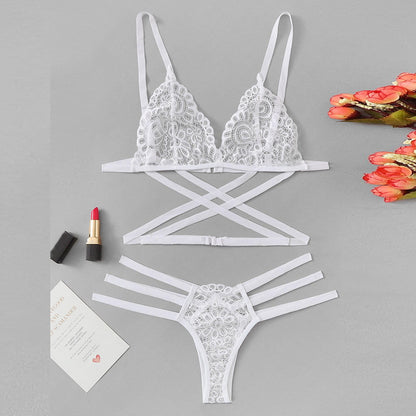 White lace lingerie set on a gray background with lipstick and flowers.