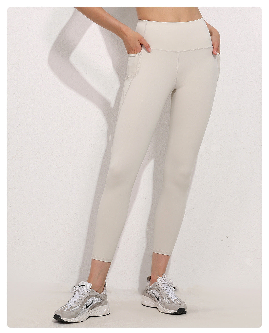 Person wearing beige leggings and gray sneakers on a white background