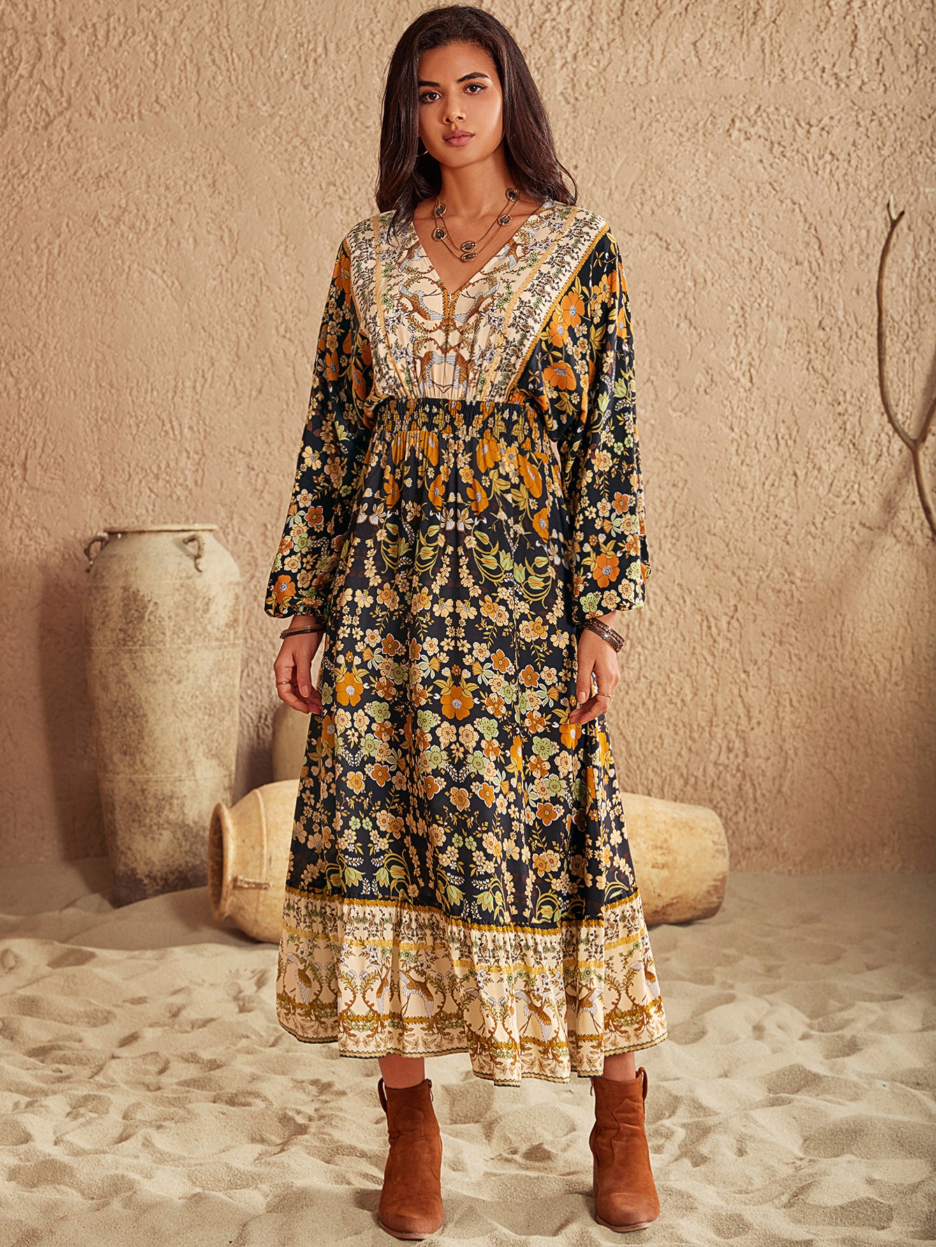 Woman wearing a long, patterned dress with long sleeves in a desert-like setting.