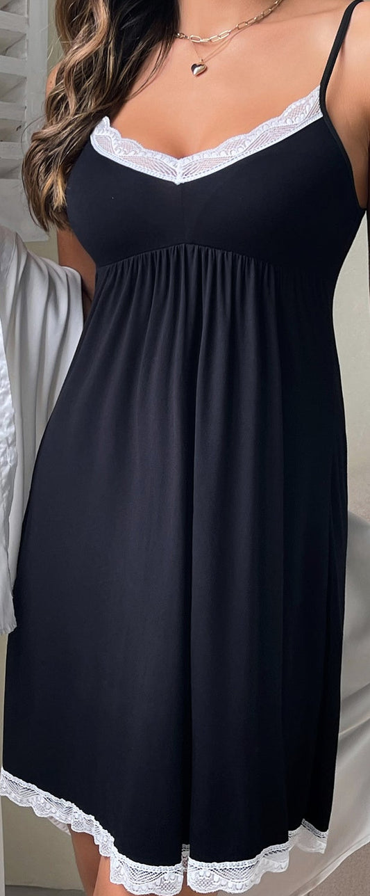 Woman wearing a black nightgown with white lace trim in a home setting.