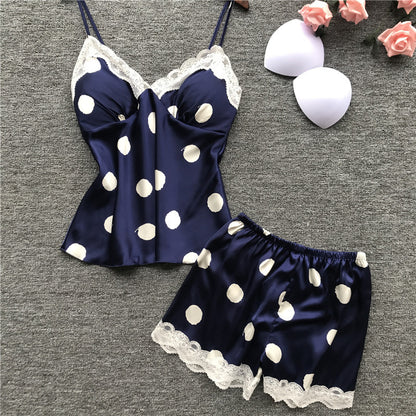 Navy blue satin nightgown with white polka dots and lace trim on a gray background.