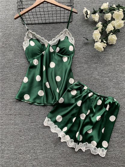 Green polka dot pajama set with lace trim on a gray surface with flowers.