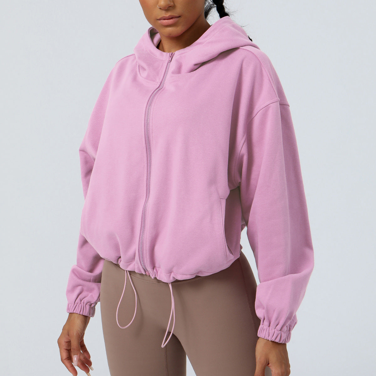 Person wearing a pink hoodie on a light gray background