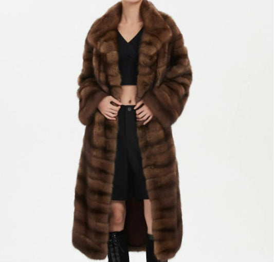 Person wearing a long brown fur coat on a white background