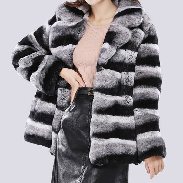 Person wearing a gray and black striped fur coat on a light gray background