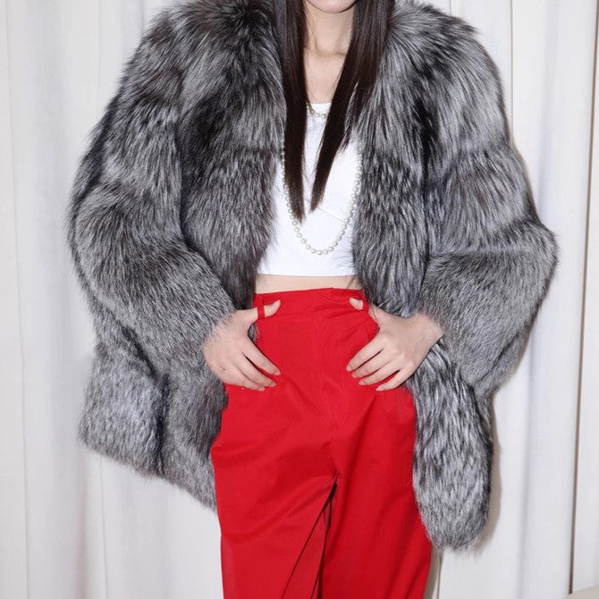 Person wearing a gray fur coat and red pants against a white background