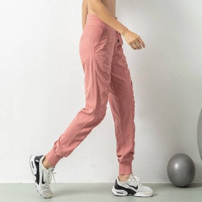 Person wearing pink jogger pants and white sneakers on a plain background