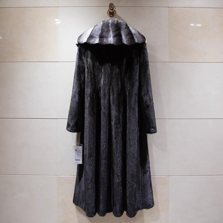 Long dark coat with fur collar on a hanger against a tiled wall.