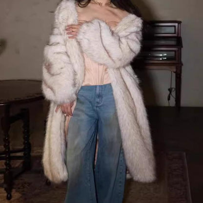 Person wearing a long white fur coat and blue jeans indoors.