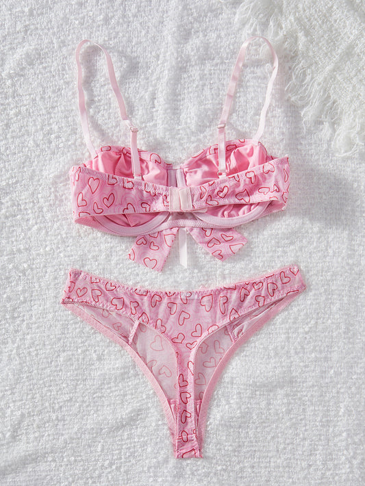 Pink lingerie set with heart patterns on a textured white background