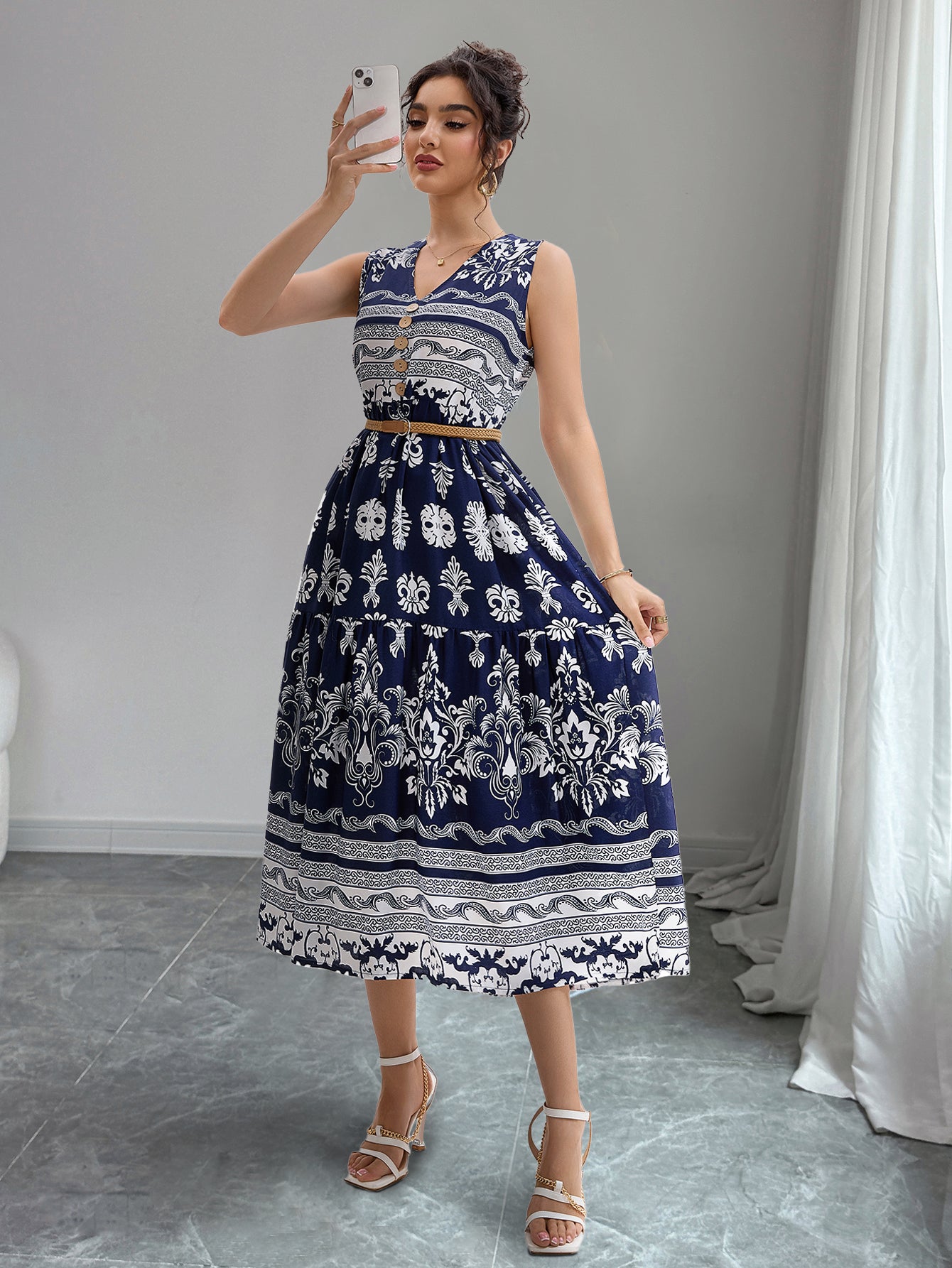 Woman taking a mirror selfie wearing a blue and white patterned dress.