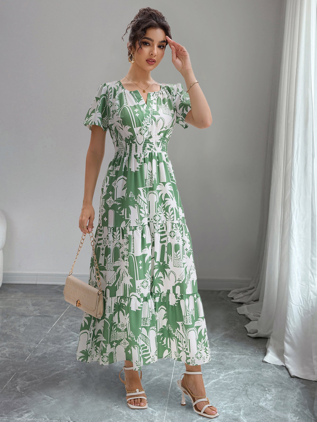 Woman wearing a green and white patterned dress in a room with gray floor and white curtains.