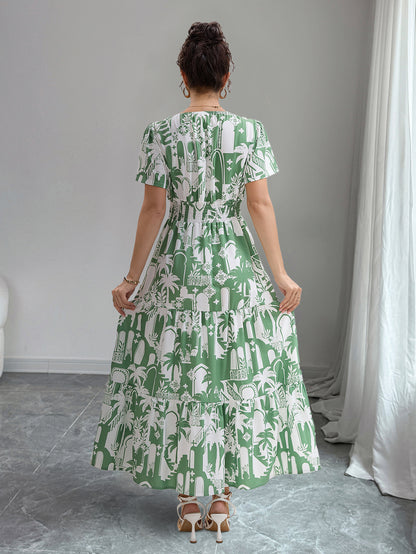 Woman wearing a green and white patterned dress in a room with gray flooring and white curtains.