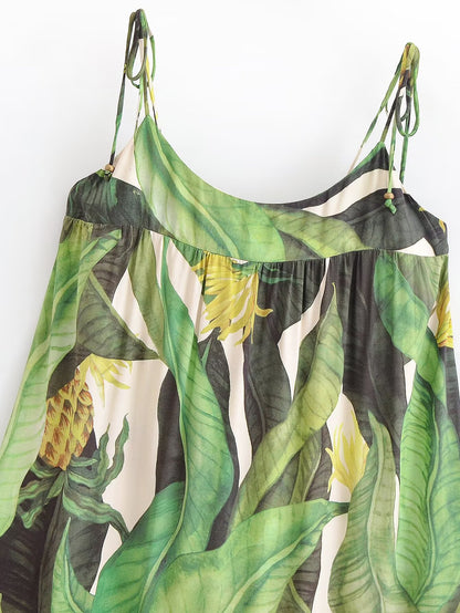 Tropical leaf patterned dress hanging against a white background