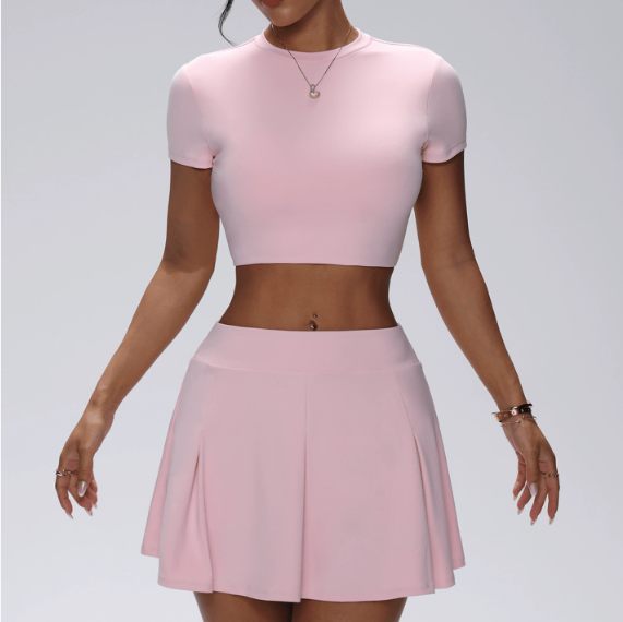Person wearing a pink crop top and skirt on a plain background