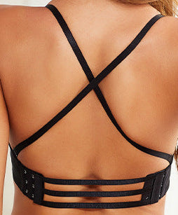 Woman wearing a black strappy bikini in a bright room.