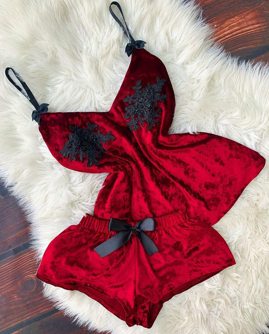 Red velvet romper with black lace details on a white fur surface