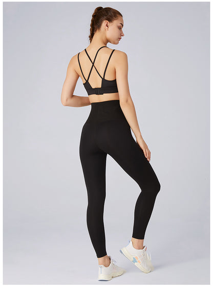 Woman wearing a black sports bra and leggings on a light gray background