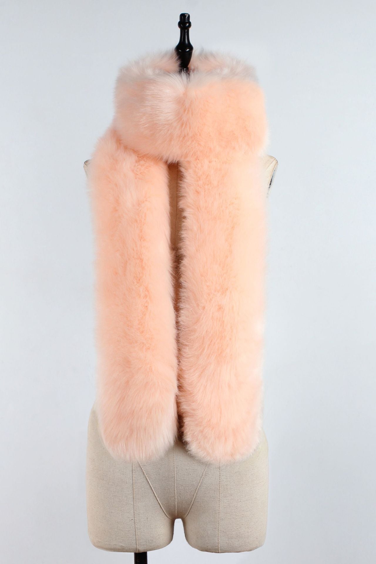 Mannequin wearing a light pink fur vest on a plain background