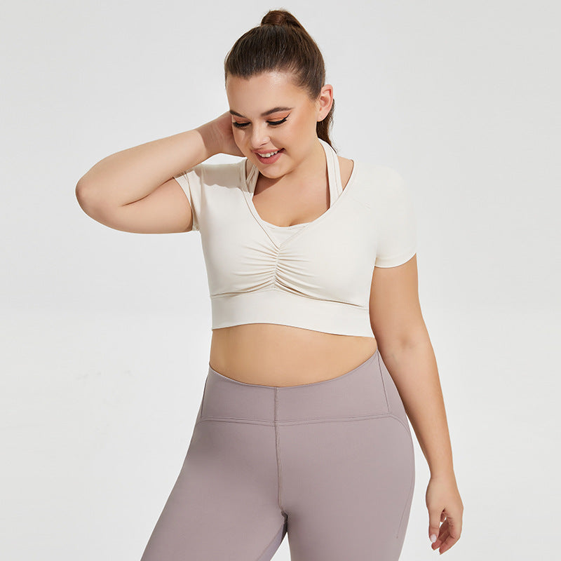 Woman wearing a white crop top and gray leggings on a light gray background