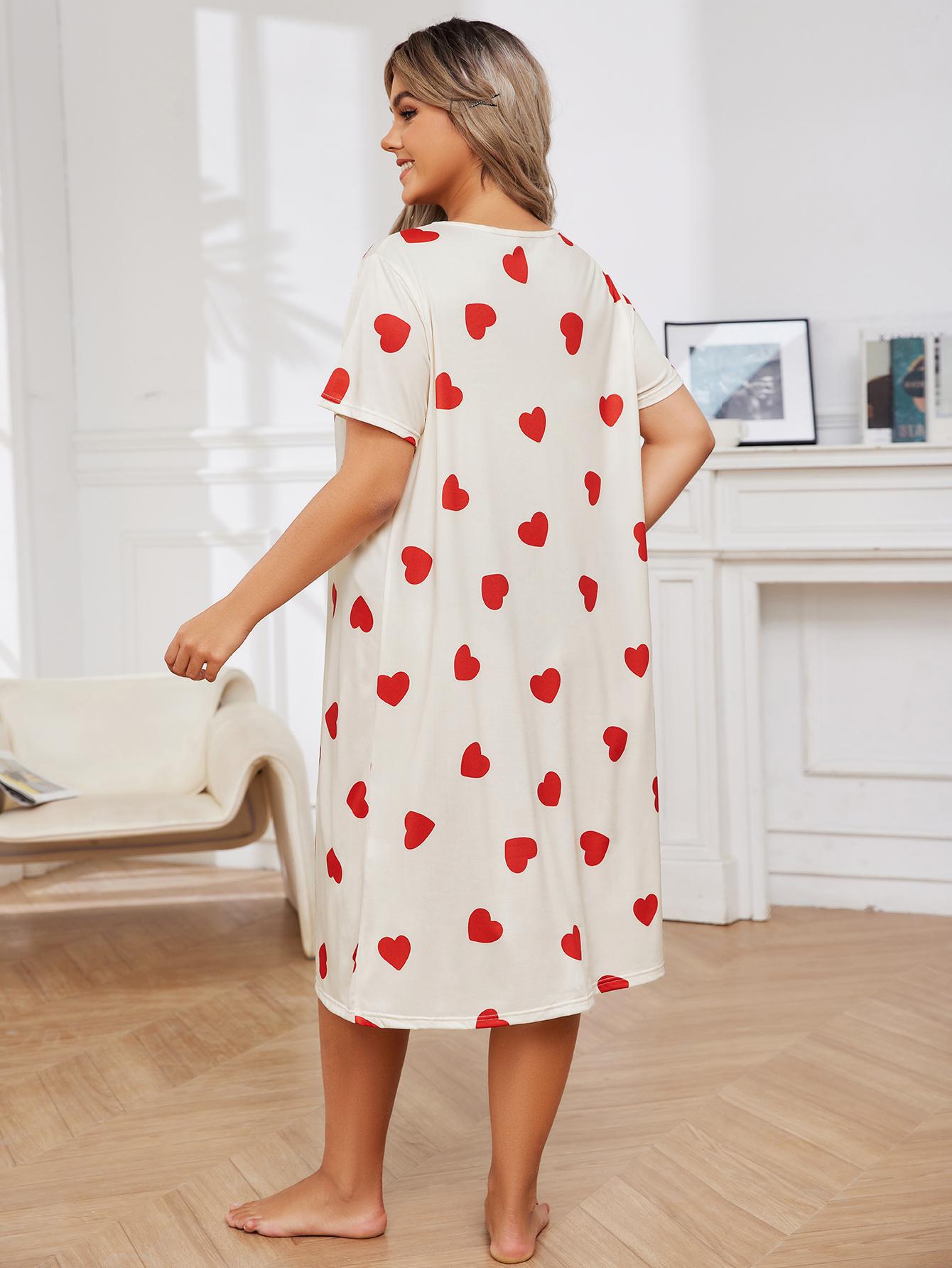 Woman wearing a white nightgown with red heart patterns in a room.